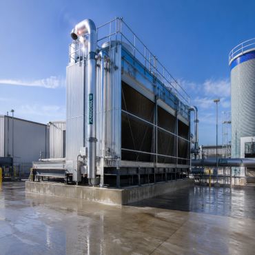 Industrial cooling tower system on a wet concrete platform, under a clear blue sky, illustrating water management solutions.