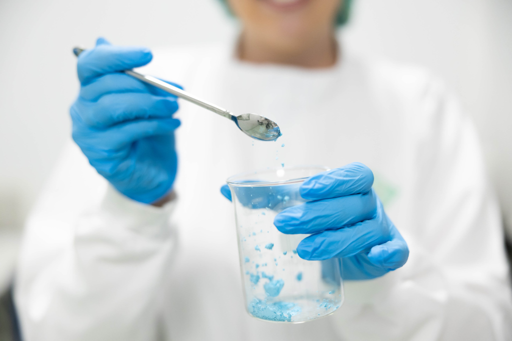 A scientist in a lab carefully handles a blue chemical substance, highlighting meticulousness and commitment to safety in water management.