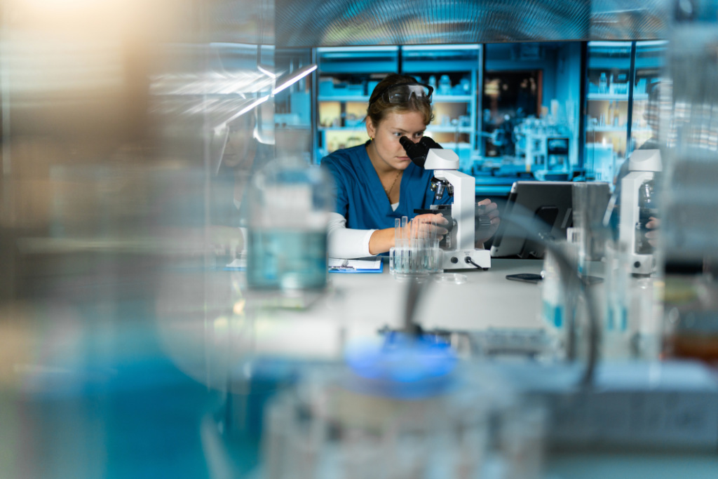 Lab technician using a microscope in a modern laboratory setting, reflecting Anderson Chemical Company's focus on innovative sanitation technologies for the food industry.