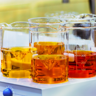 Laboratory beakers filled with amber-colored liquids on a countertop, representing chemical formulation processes.